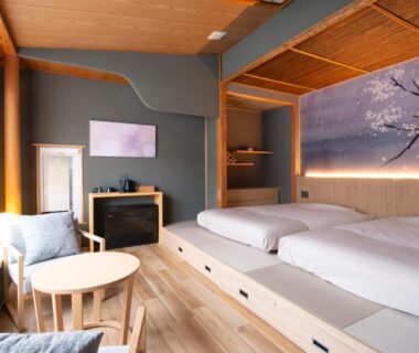 Japanese tatami room with futon beds, low table by window, wooden interior and decorative wall mural, Kamikura Matsurube Onsen Iwate