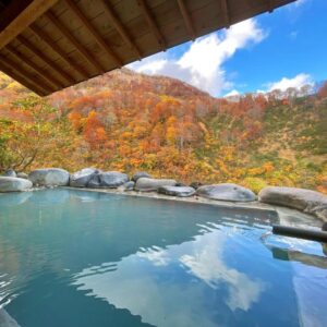 Outdoor stone onsen reflecting sky and autumn foliage, Hitō Hanabun, Niigata, Chūbu, Japan