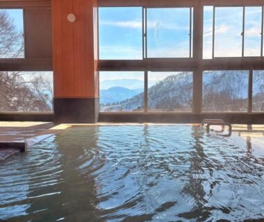 Indoor onsen bath with large windows overlooking snowy mountains at Hitō Hanabun, Niigata