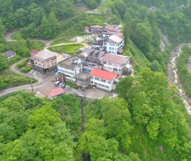 Aerial view of hillside ryokan Hitō Hanabun surrounded by dense forest above a river in Niigata, Chūbu Japan