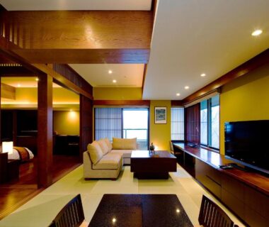 Spacious tatami room with sofa, low table, sliding screens and TV at Chikusenso Onsen, Miyagi