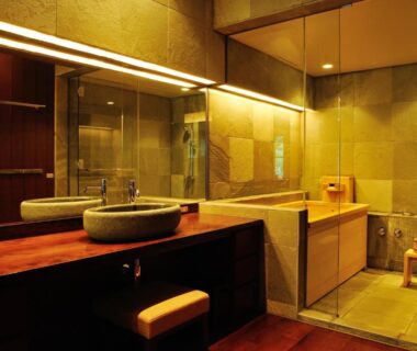Indoor bathing area with wooden counter, stone sink, glass partition and shower stool at Chikusenso Onsen, Miyagi
