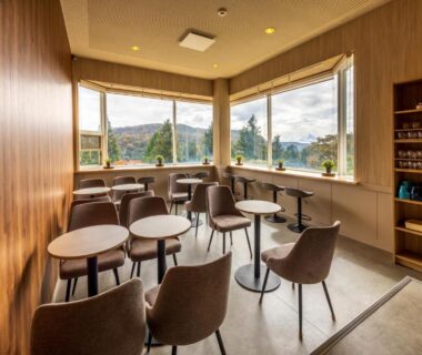 Lounge with stools and round tables and large corner windows at 箱根芦ノ湖 HOTEL RaKuun, Kanagawa