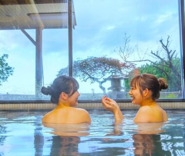 Two people in indoor onsen at Shinpachiya Mie with garden visible through large window