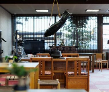 Wooden seating area with decorative fish sculpture and lattice windows at Ryokufuen Kiyoharu, Gifu
