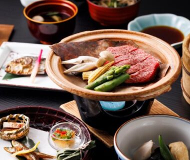 Assorted traditional Japanese dishes on low wooden table including grilled meat, tempura, soups and small bowls