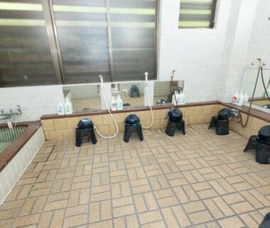 Indoor wash stations with stools, handheld showers, mirrors and tiled floor at Naeba Lodge Oka, Niigata