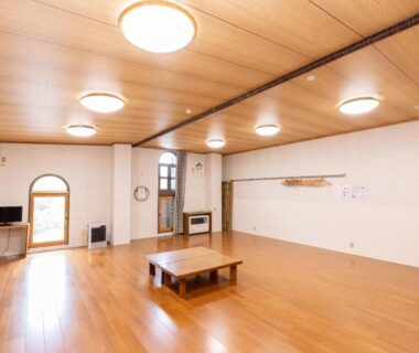 Spacious wooden floor communal lounge with low table and TV at Naeba Lodge Oka in Niigata