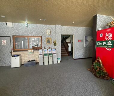 Lobby area with red vending machine, reception counter, recycling bins and staircase at Naeba Lodge Oka, Niigata, Chūbu Japan