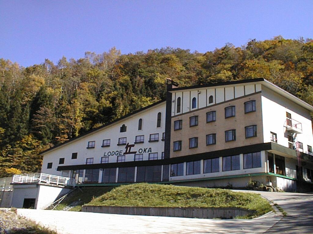 Exterior view Naeba Lodge Oka Niigata Three-story lodge on wooded hillside with driveway and balconies at Naeba Lodge Oka, Niigata
