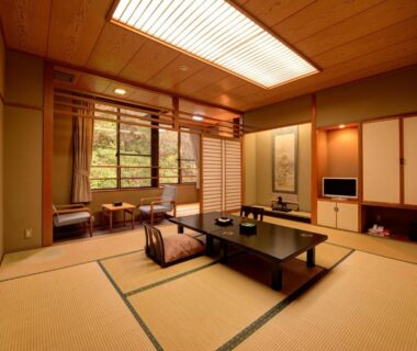 Tatami room with low table, zabuton cushions, shoji screens and view of garden greenery