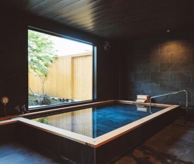 Rectangular indoor bath with wooden rim and garden view at 蓼科BASE kitchen spa & hotel, Nagano