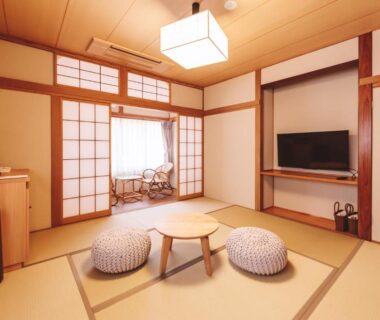 Tatami room with low round table, zabuton cushions, shoji screens and TV at 蓼科BASE kitchen,spa&hotel Nagano