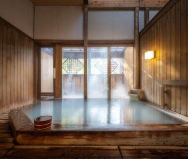 Wooden indoor onsen bath with wooden bucket and frosted windows at Kinosato Zaō, Yamagata
