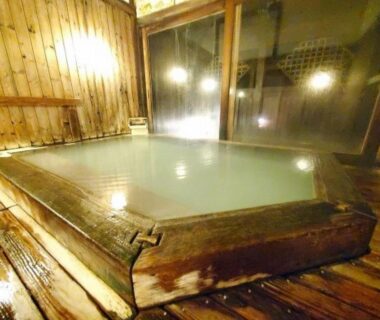 Indoor wooden onsen bath with milky water and soft lighting at Kinosato Zaō Onsen, Yamagata