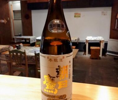 Large sake bottle on wooden counter in Ringoya dining area at Zaō Onsen, interior with tables and chairs