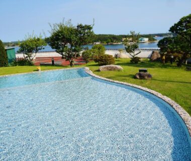 Curved outdoor pool and lawn at Kashikojima Park Hotel Michishio with coastal bay and boats in Mie, Kansai