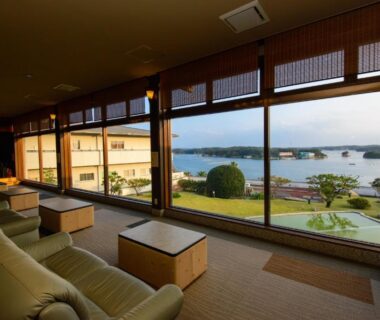 Seating area with sofas and low tables facing bay and garden at Kashikojima Park Hotel Michishio