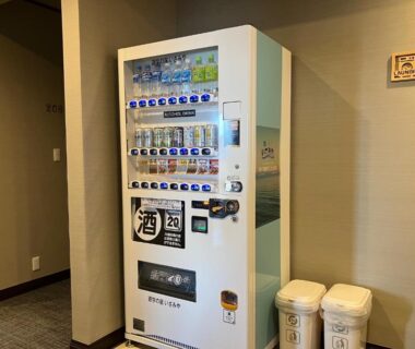 White beverage vending machine in Isamiya auberge hallway next to recycling bins in Fukushima ryokan