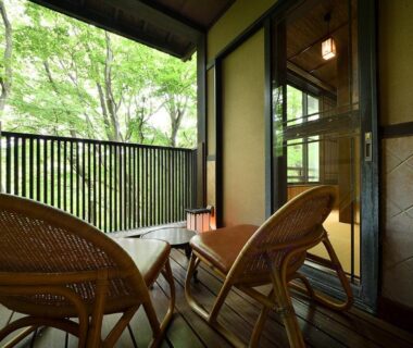 Balcony with wicker chairs and small table overlooking verdant trees at Sansuikaku in Nasu, Tochigi