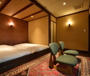Warm-lit twin bed guest room with low chairs and patterned rug at Sansuikaku in Nasu, Tochigi