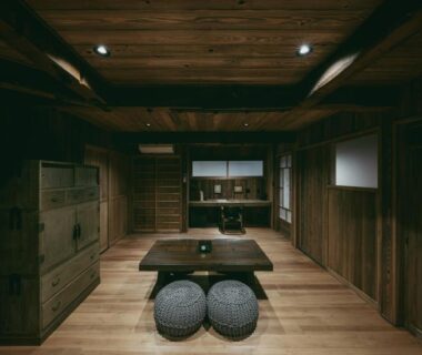 Low wooden lounge with low table and round floor cushions at 酒蔵宿西山 鼓傳 -koden- in Hyōgo, Japan