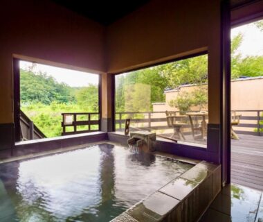 Indoor onsen bath with wooden deck and garden view at Sato no Yu Waraku, Kumamoto, Kyūshū