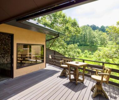 Wooden terrace with table and chairs overlooking lush forest at Sato no Yu Waraku in Kumamoto, Kyūshū