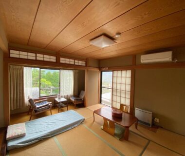 Traditional tatami room with low table, futon mattress, shoji screens and garden view in Kanagawa ryokan