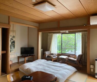 Tatami room with futon, low table and window seating at 金閣莊 in Kanagawa