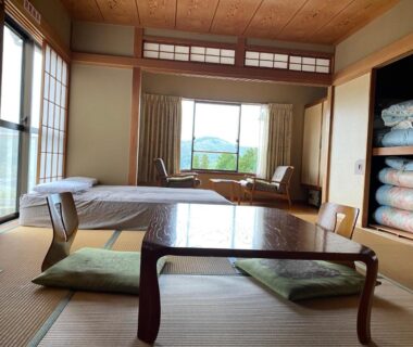Tatami room with low table, floor cushions and folded futon at 金閣莊 in Kanagawa, Kantō, Japan