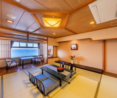 Tatami room with low table, zabuton cushions and shoji screens overlooking water at Choshi Grand Hotel, Chiba