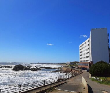 Hotel facing rocky shoreline with waves and coastal walkway in Choshi, Chiba