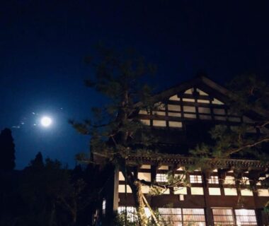 Moonlit traditional ryokan facade with lit windows and trees, Zenigame in Chūbu, Ishikawa, Japan