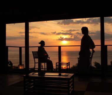 Guests silhouetted on tatami balcony watching sunset over the sea at Sumihei, Taiza Onsen, Kyoto