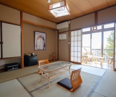 Tatami room with low table, zaisu chairs and balcony overlooking garden at Abekura Onsen Kanagawa