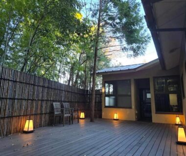 Wooden outdoor deck with lanterns, bamboo fence and chairs at Abekura Onsen in Kanagawa, Kantō, Japan