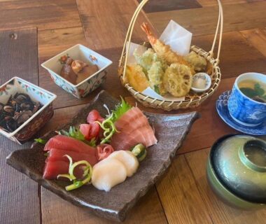 Assorted sashimi (tuna and scallop), tempura basket, side dishes and chawanmushi on wooden table at Abekura Onsen