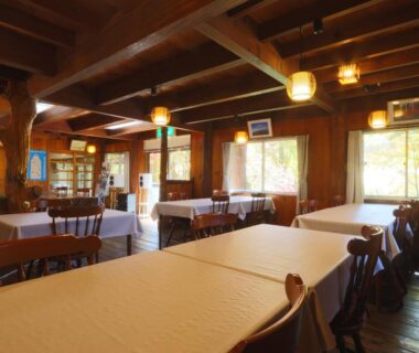 Interior dining area with wooden beams and tablecloths at Suzumenoyado Yagura in Nagano