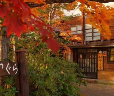 Wooden ryokan entrance with shoji doors and red maple leaves in Nagano