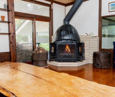 Wood slab table and central wood-burning stove in Okara Sansō lounge, Nagano