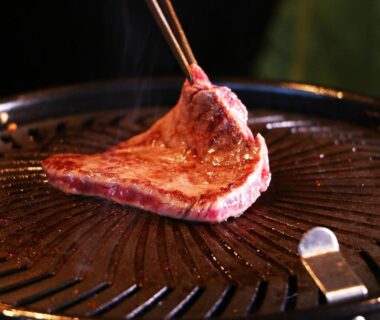 Thin slice of beef being grilled on a tabletop grill with chopsticks at Gesseitei ryokan in Hyogo