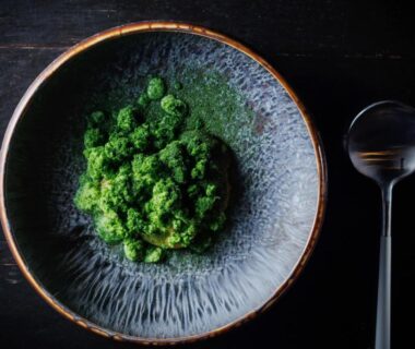 Ceramic bowl with green herb garnish and spoon on dark wood table at Kaze no Sawa, Miyagi