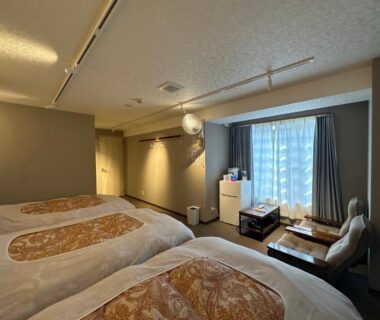 Three single beds with low table and window seating at Hôtel Ekihon Building, Niigata, Chūbu, Japan