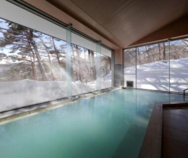 Indoor onsen bath with floor-to-ceiling windows overlooking snowy landscape and trees at Kagetsu Highland, Takayu Onsen, Fukushima