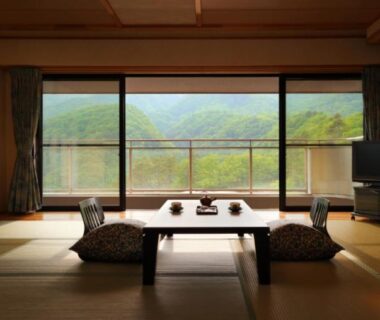 Tatami room with low table, cushions and wide window overlooking mountains at Kagetsu Highland Hotel, Takayu Onsen