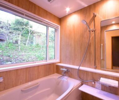 Indoor wooden bathtub and shower with large window overlooking forested garden at Koyasan Shukubo Sanboin, Wakayama