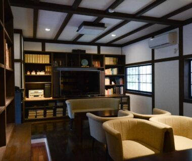 Japanese lounge with cushioned armchairs, bookshelf, low table and wooden beams at Koyasan Shukubo Fudoin in Wakayama