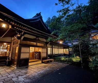 Traditional wooden ryokan entrance lit at dusk with stone pathway and garden, Komyoin Koyasan Wakayama