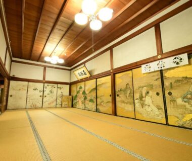 Large tatami room with painted fusuma panels and wooden ceiling at Koyasan shukubo Komyoin in Wakayama